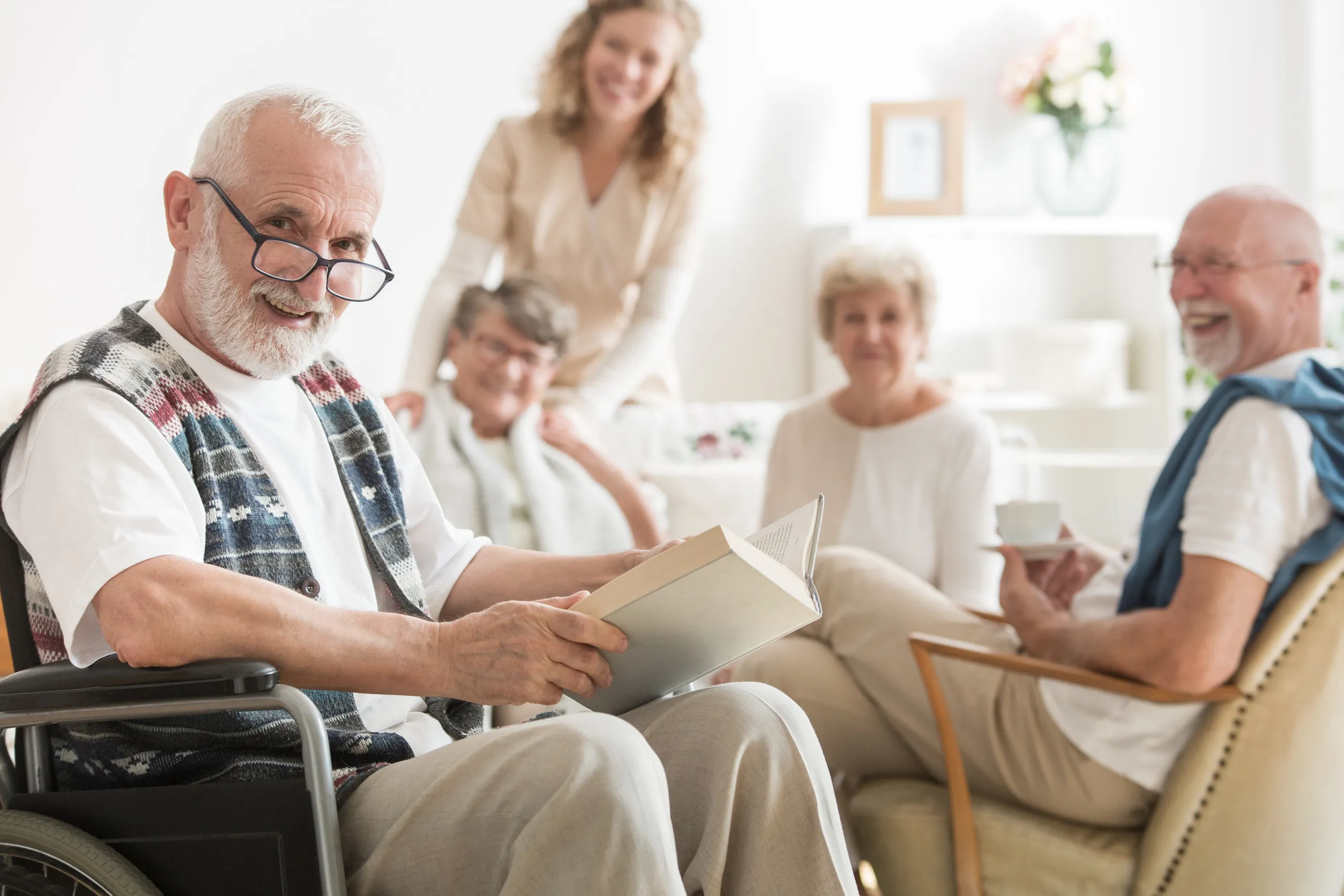 Old man with glasses sitting on wheelchair reading a book Old man with glasses sitting on wheelchair reading a book